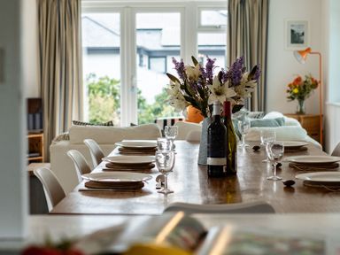 A dining table set with plates, wine bottles, and flowers in a living room at Corriana in Rock