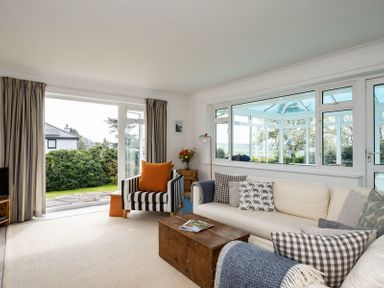 A living room with a sofa and armchair next to large windows and a glass door at Corriana in Rock