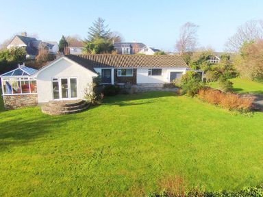 A single story house with a conservatory and a green lawn at Corriana in Rock