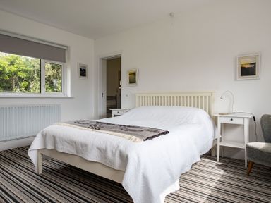 A bedroom with a white bed and striped carpet at Corriana in Rock