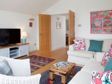 A living room with a sofa a TV on a cabinet a wooden table and patterned rugs at Drifters in Rock