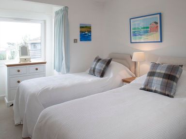 A bedroom with two single beds white bedspreads plaid pillows a dresser with a mirror and paintings on the walls at Drifters in Rock