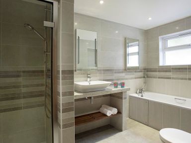 A bathroom with a shower, a sink with two mirrors above it, a bathtub, and a window at Drifters Rock