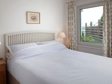 A bedroom with a bed a bedside lamp a window with curtains and a painting on the wall at Drifters Rock