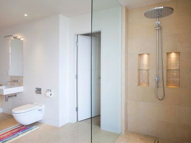 A bathroom with a wall-mounted toilet sink a large shower with two niches and a glass partition at Downalong in Daymer Bay