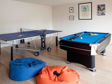 A game room with a ping pong table pool table two bean bags and framed pictures on the wall at Downalong in Daymer Bay