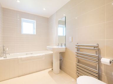 A bathroom with a bathtub sink mirror and towel rail at Chy-An-Dowr in Rock
