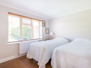 A bedroom with two single beds covered with white bedspreads a lamp and framed pictures on the wall at Chy-An-Dowr in Rock