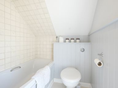 A bathroom with a bathtub a toilet and containers on a shelf at Sandy Lodge Rock in Rock