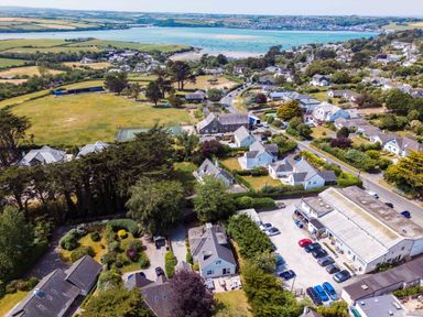 An aerial view of a coastal village with houses roads trees a parking lot and a body of water in the background at Sandy Lodge Rock in Rock