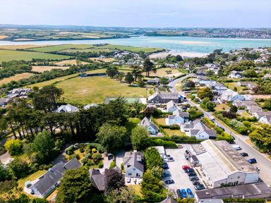 An aerial view of a coastal village with houses roads trees a parking lot and fields near the water at Sandy Lodge Rock