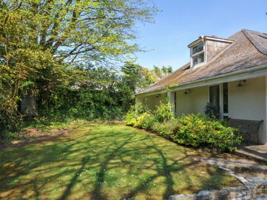 A yard with grass and a tree next to a house with plants along the side at Sandy Lodge Rock in Rock