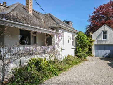 An exterior view of a white house with a gravel driveway and detached garage at Sandy Lodge Rock