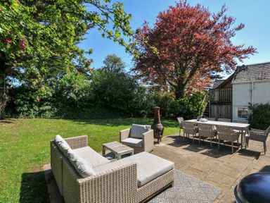 An outdoor patio with wicker sofa and chairs a dining table with chairs and trees at Sandy Lodge Rock in Rock