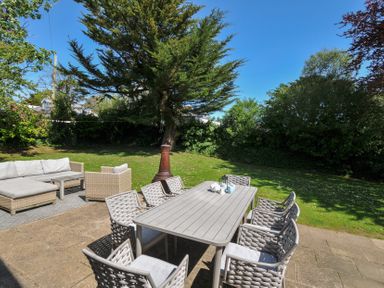An outdoor patio with a dining table and chairs and a seating area with a sofa and armchair in a garden at Sandy Lodge Rock in Rock