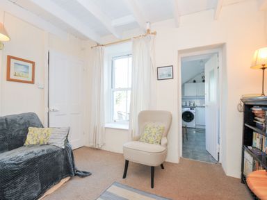 A living room with a sofa and armchair at Coppingers Cottage in Polzeath