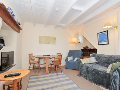 A living room with a sofa and dining table at Coppingers Cottage in Polzeath