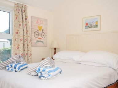 A bedroom with a bed and towels at Coppingers Cottage Polzeath