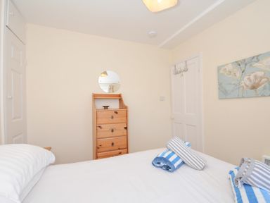 A bedroom with a bed, dresser, and mirror at Coppingers Cottage in Polzeath