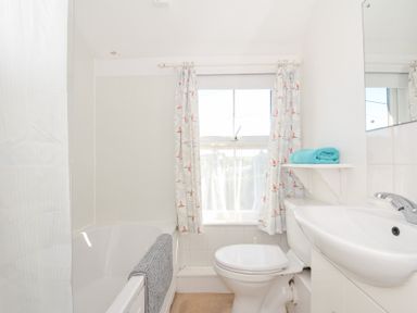 A bathroom with a bathtub, toilet, and sink at Coppingers Cottage in Polzeath