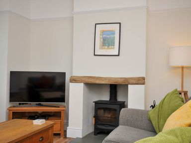 A living room with a television, coffee table, and stove at The Porthole in Port Isaac
