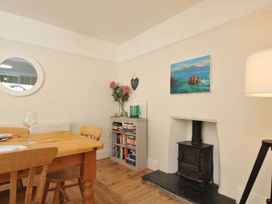 A dining room with a table and chairs and a wood stove at The Porthole in Port Isaac