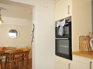 A kitchen with an oven and dining area at The Porthole in Port Isaac