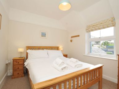 A bedroom with a bed, nightstand, and lamp at The Porthole in Port Isaac