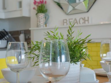 A dining table set with glassware white bowls and a plant in a white pot in a kitchen at The View in Port Isaac