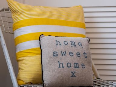 A chair with two cushions one striped yellow and white and one with home sweet home text at The View in Port Isaac