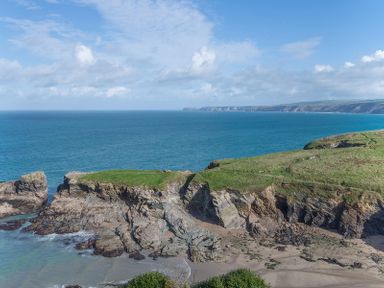 Rocky coastline with green grass cliffs and ocean water at The View in Port Isaac