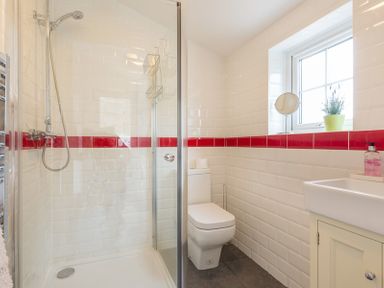 A bathroom with a shower enclosure toilet sink and window at Beehive Cottage in Port Isaac