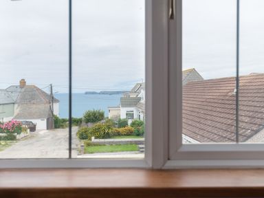 A view of houses and the sea through a window at Fairholme in Port Isaac