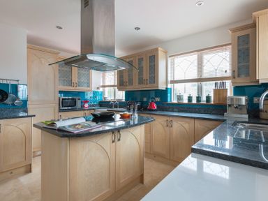 A kitchen with wooden cabinets and a central island with a book and pan at Fairholme in Port Isaac