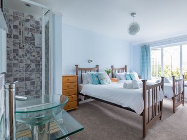 A bedroom with two single beds a glass sink and a shower at Fairholme in Port Isaac