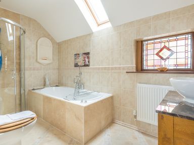 A bathroom with a bathtub shower toilet and stained glass window at Fairholme in Port Isaac