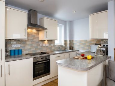 A kitchen with cabinets countertops stove oven and a window at The Hideaway in Port Isaac