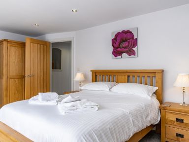 A bedroom with a wooden bed and bedside tables with lamps and a wardrobe at The Hideaway in Port Isaac