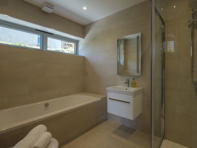 A bathroom with a bathtub a sink with a mirror a shower and towels at Point Break in Polzeath