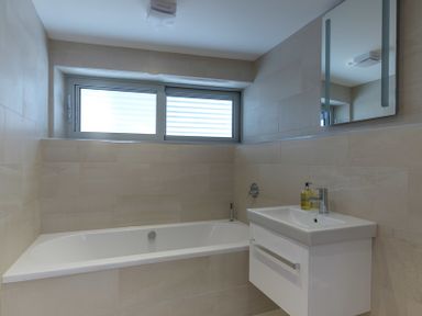 A bathroom with a bathtub a sink with liquid soap and a mirror above at Point Break in Polzeath