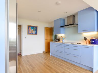 A kitchen with blue cabinets wooden floor and kitchen utensils at Sea Mist in Polzeath