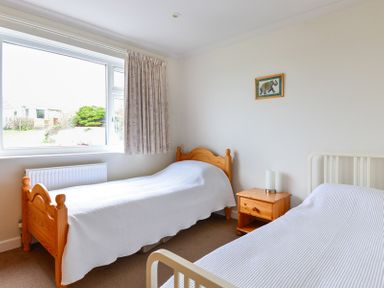 A bedroom with two single beds and a wooden nightstand at Sea Mist in Polzeath