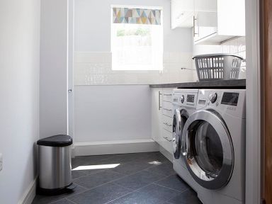 A laundry room with a washing machine dishwasher a countertop and a laundry basket on the counter
