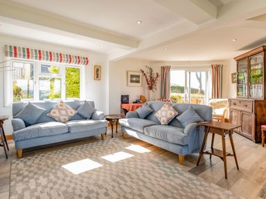 A living room with two blue sofas and patterned cushions at Trevan House Lundy in Polzeath