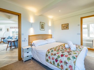 A bedroom with a double bed and floral canopy and a side table with drawers at Trevan House Lundy in Polzeath
