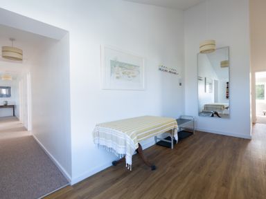 A hallway with a table covered with a cloth a long rectangular mirror a coat rack and wooden flooring at Windyhill in Polzeath