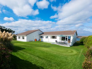 A house with a lawn and outdoor seating area at Windyhill in Polzeath