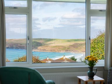 A view of the sea and landscape through a window at Windyhill in Polzeath