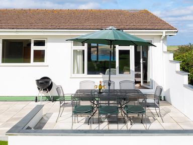 An outdoor dining area with a table and chairs at Windyhill in Polzeath