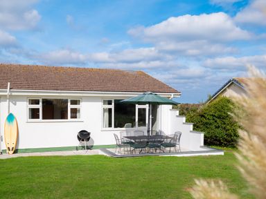 An outdoor patio with furniture and a surfboard at Windyhill in Polzeath